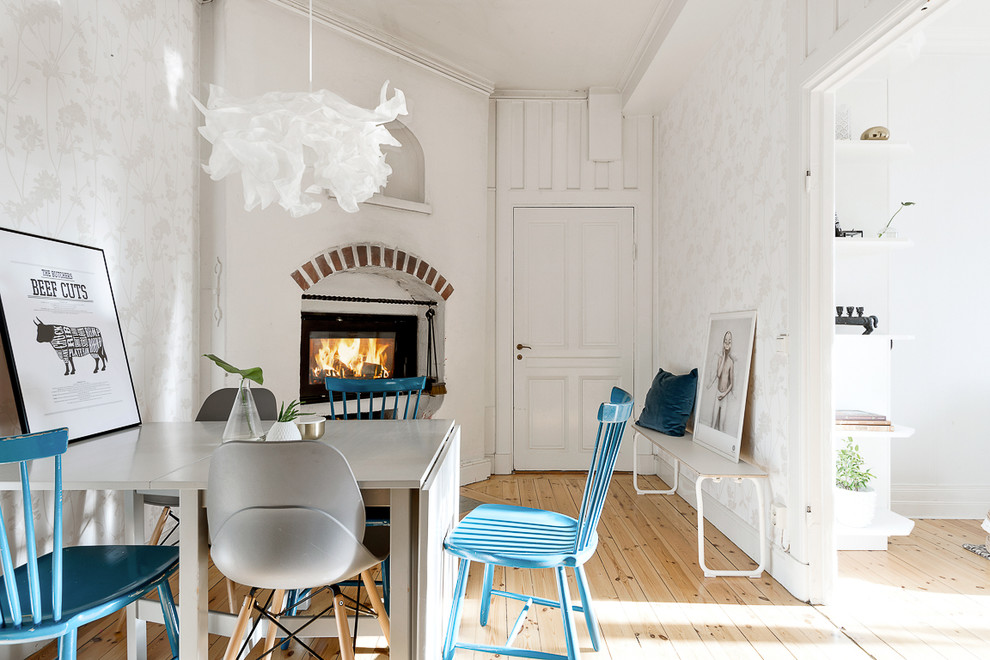 Immagine di una sala da pranzo scandinava di medie dimensioni con pareti bianche, parquet chiaro e camino classico