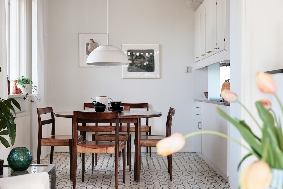 На фото: кухня-столовая в скандинавском стиле с белыми стенами и белым полом с
