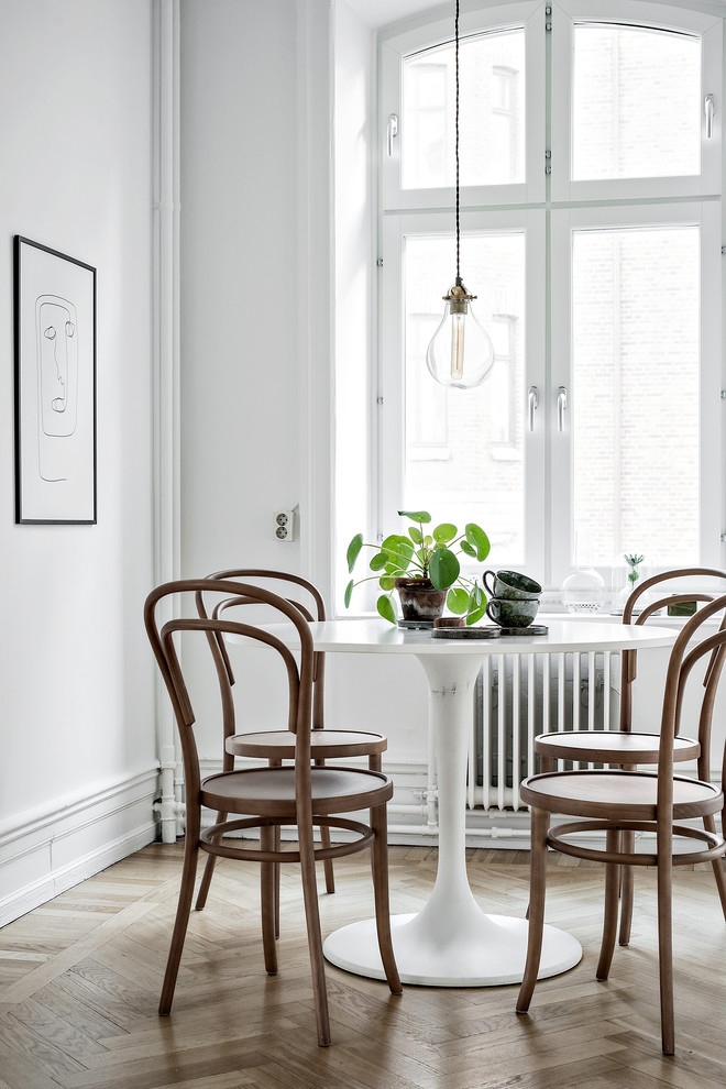 Foto di una piccola sala da pranzo aperta verso la cucina nordica con pareti bianche, parquet chiaro e pavimento beige
