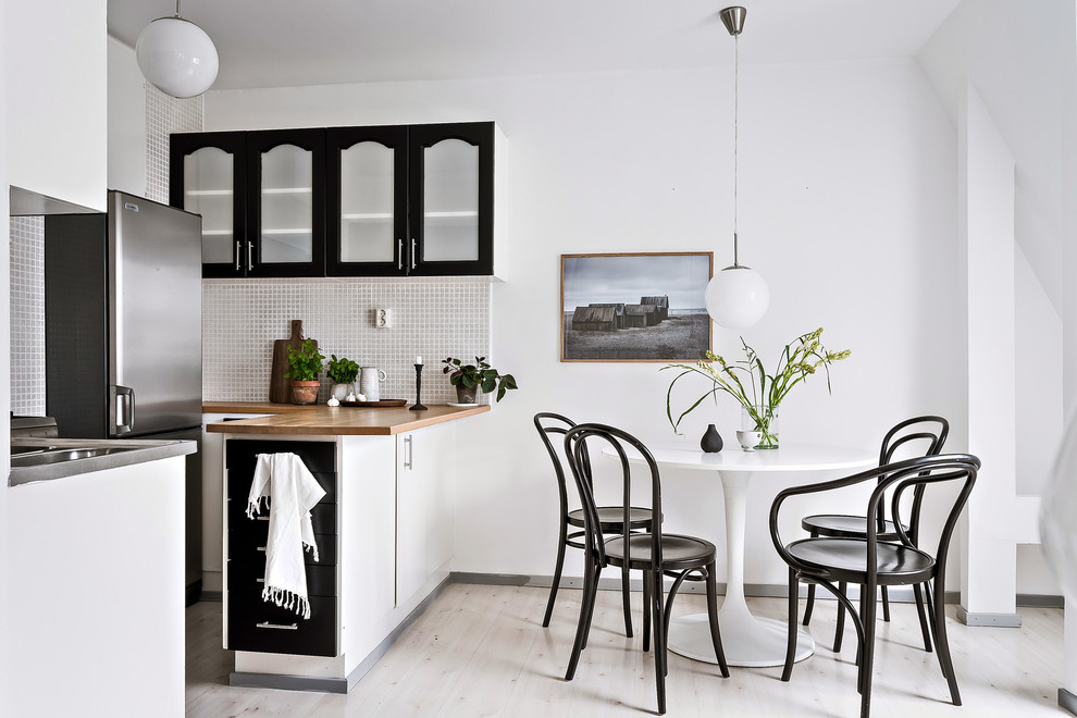 Cette image montre une petite salle à manger ouverte sur la cuisine nordique avec un mur blanc, parquet clair et un sol beige.