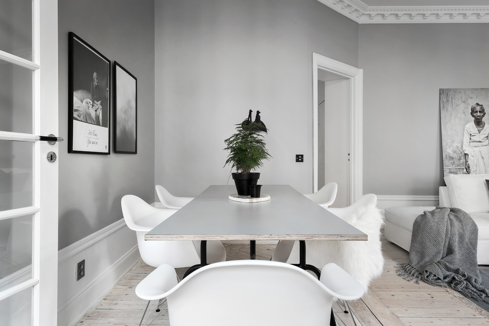 Imagen de comedor escandinavo de tamaño medio abierto sin chimenea con paredes grises y suelo de madera clara