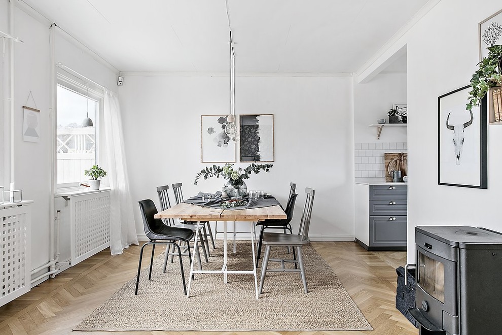 Foto de comedor nórdico con paredes blancas, suelo de madera clara, estufa de leña y suelo beige