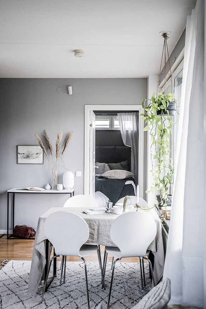 На фото: столовая в скандинавском стиле с серыми стенами, паркетным полом среднего тона и коричневым полом с