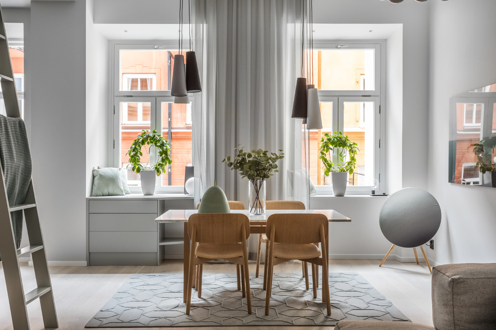 Medium sized scandinavian open plan dining room in Stockholm with grey walls, light hardwood flooring, beige floors and feature lighting.