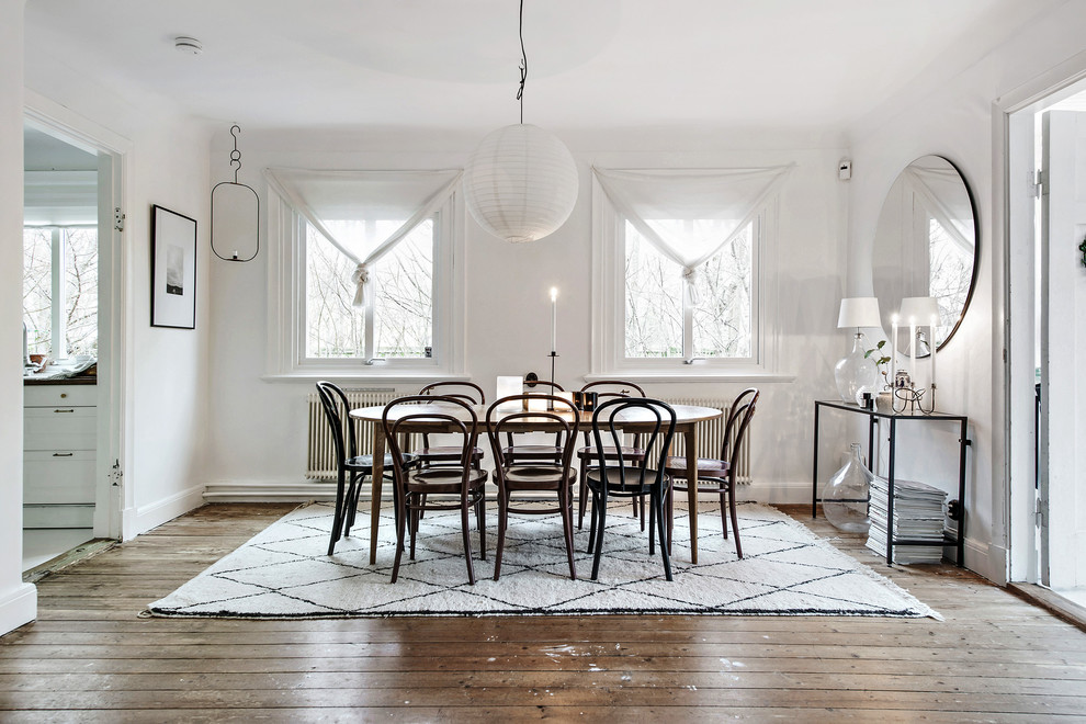 Immagine di una sala da pranzo scandinava chiusa e di medie dimensioni con pareti bianche, pavimento in legno massello medio e pavimento marrone