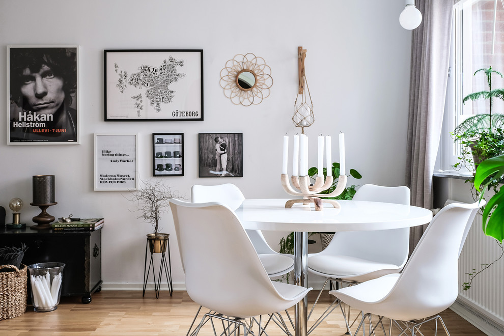 На фото: столовая в скандинавском стиле с белыми стенами, светлым паркетным полом и бежевым полом без камина с