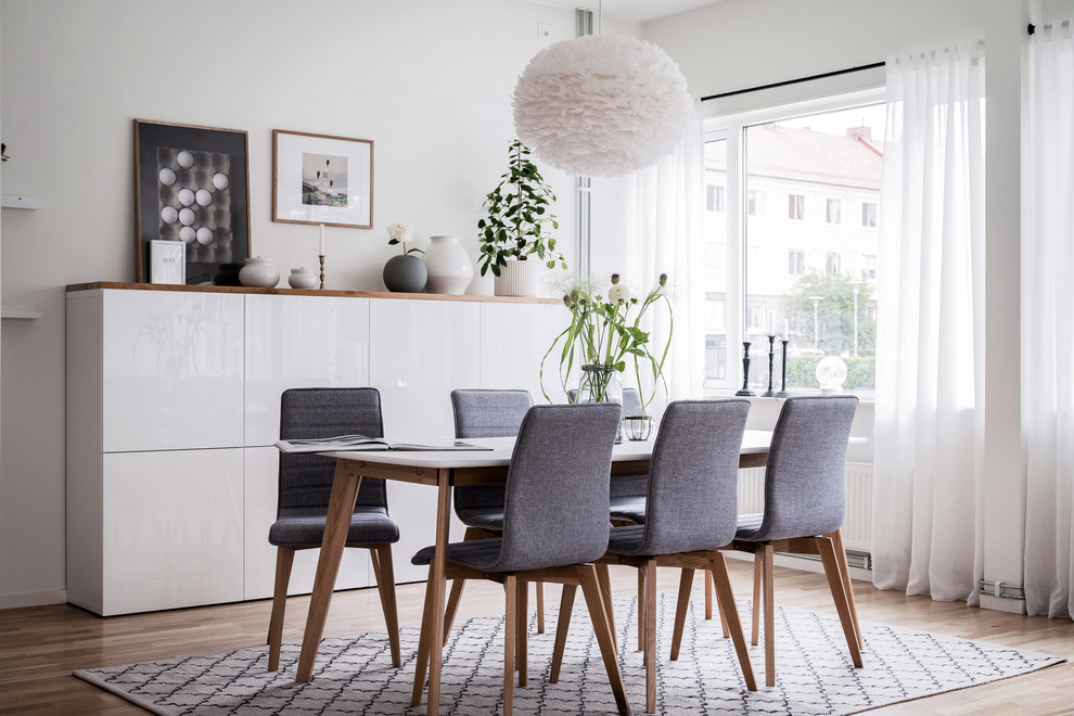 Idee per una sala da pranzo scandinava con pareti bianche, parquet chiaro e pavimento beige