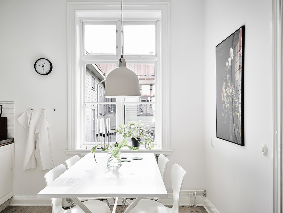 Immagine di una sala da pranzo scandinava chiusa e di medie dimensioni con pareti bianche, pavimento in legno massello medio e nessun camino