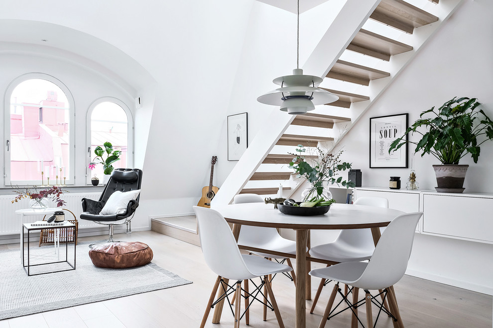 На фото: гостиная-столовая в скандинавском стиле с белыми стенами и бежевым полом без камина с