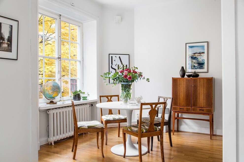 Cette photo montre une salle à manger scandinave fermée et de taille moyenne avec un mur blanc et un sol en bois brun.