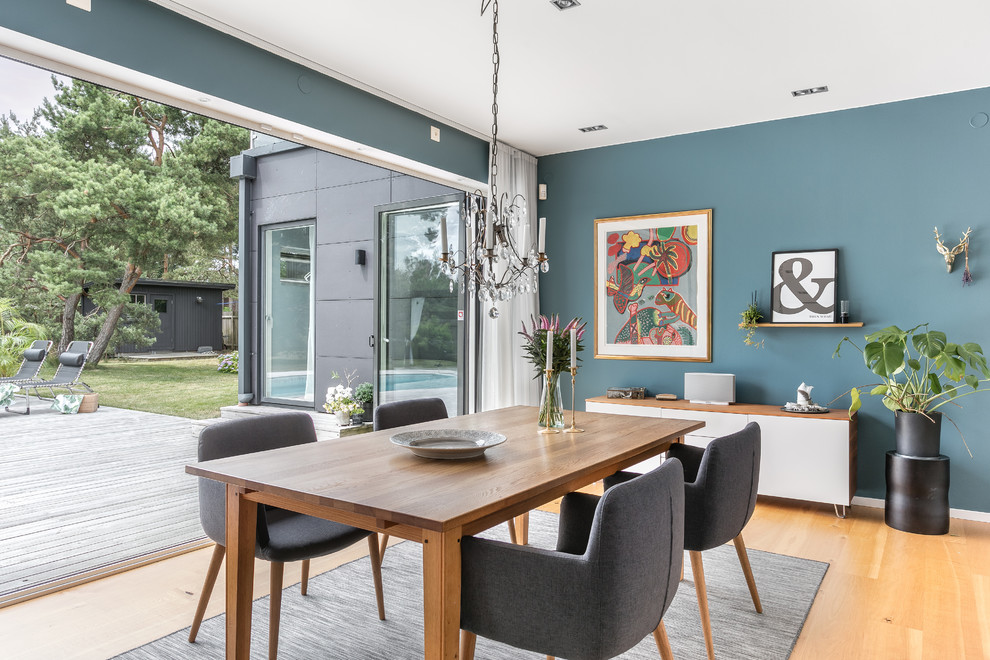 Ejemplo de comedor moderno de tamaño medio con paredes azules, suelo de madera clara y suelo beige