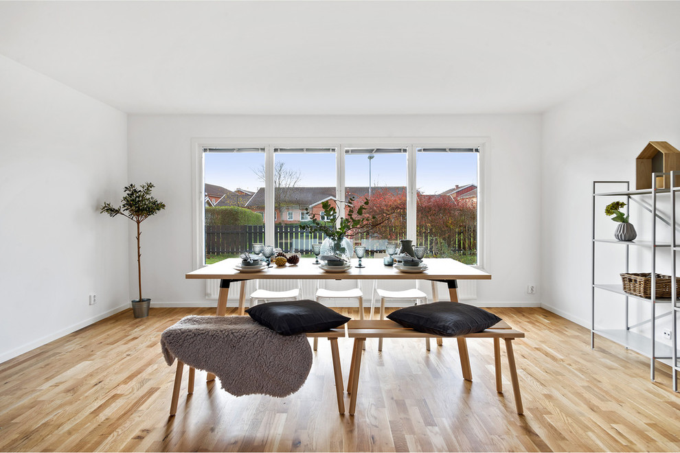 Cette image montre une salle à manger nordique avec un mur blanc, parquet clair et un sol beige.
