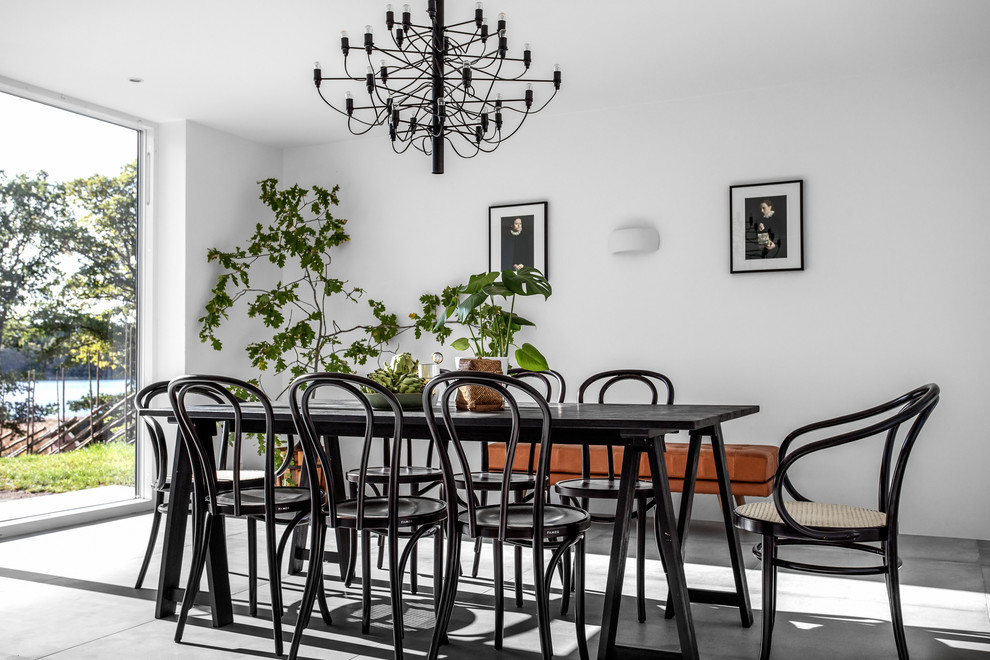 На фото: гостиная-столовая среднего размера в скандинавском стиле с белыми стенами, бетонным полом и серым полом