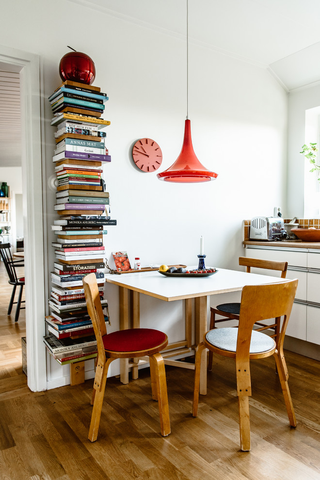 На фото: кухня-столовая в скандинавском стиле с белыми стенами, паркетным полом среднего тона и коричневым полом