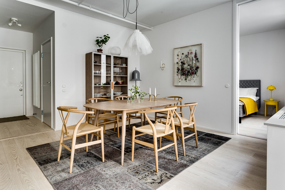 Foto di una sala da pranzo aperta verso il soggiorno scandinava di medie dimensioni con pareti bianche e parquet chiaro