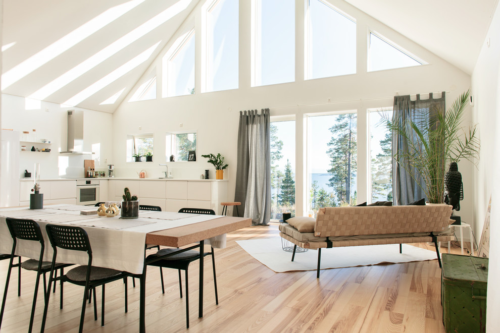 Geräumige Skandinavische Wohnküche ohne Kamin mit weißer Wandfarbe und hellem Holzboden in Sonstige