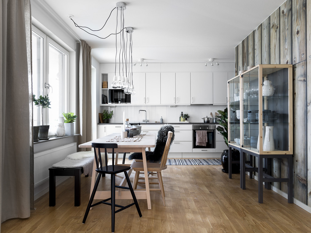Пример оригинального дизайна: кухня-столовая среднего размера в скандинавском стиле с паркетным полом среднего тона, разноцветными стенами и коричневым полом без камина