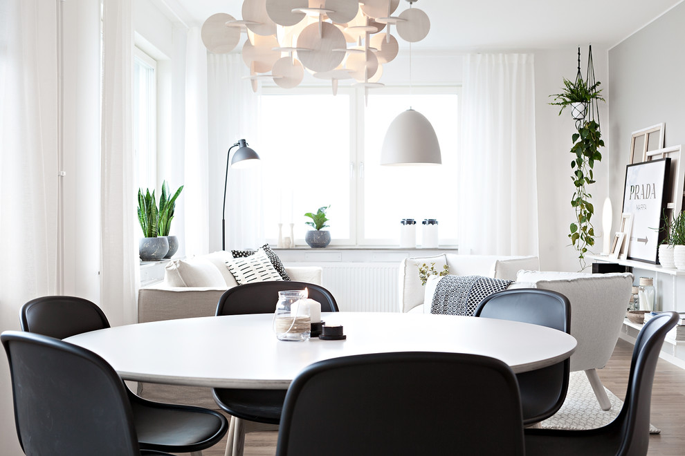 Scandinavian kitchen/dining room in Gothenburg with white walls, light hardwood flooring and brown floors.