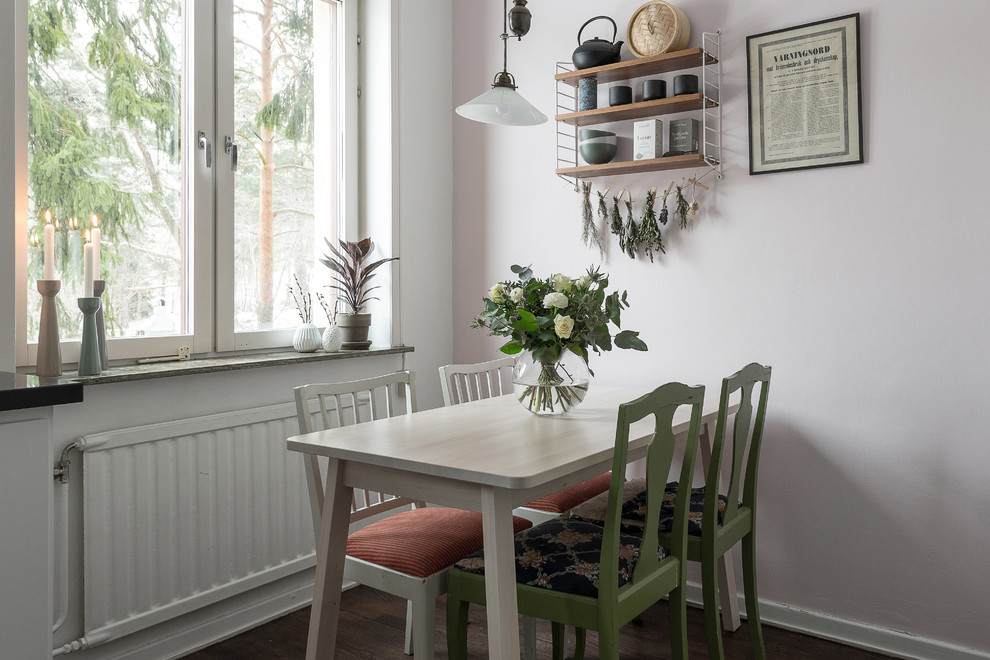 Small scandi dining room in Stockholm with pink walls, dark hardwood flooring and brown floors.