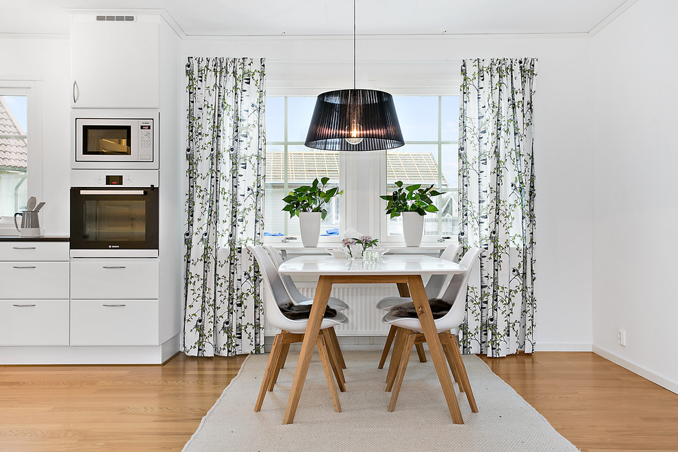Diseño de comedor de cocina escandinavo de tamaño medio sin chimenea con paredes blancas y suelo de madera en tonos medios