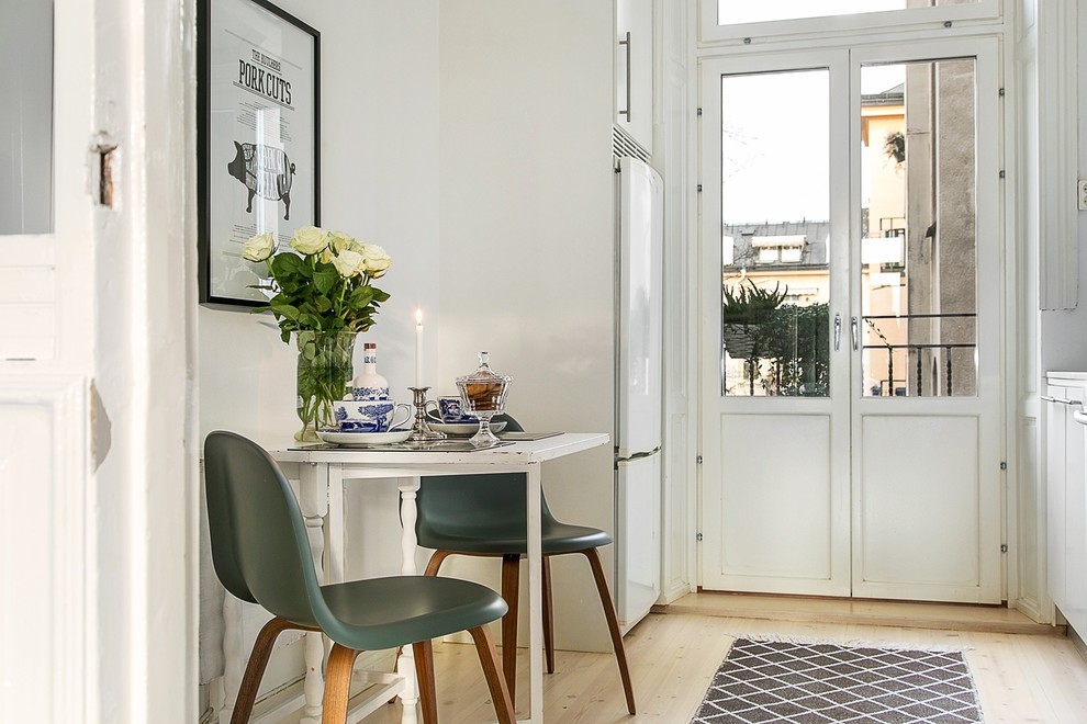 Photo of a small scandi kitchen/dining room in Stockholm with white walls, light hardwood flooring and no fireplace.