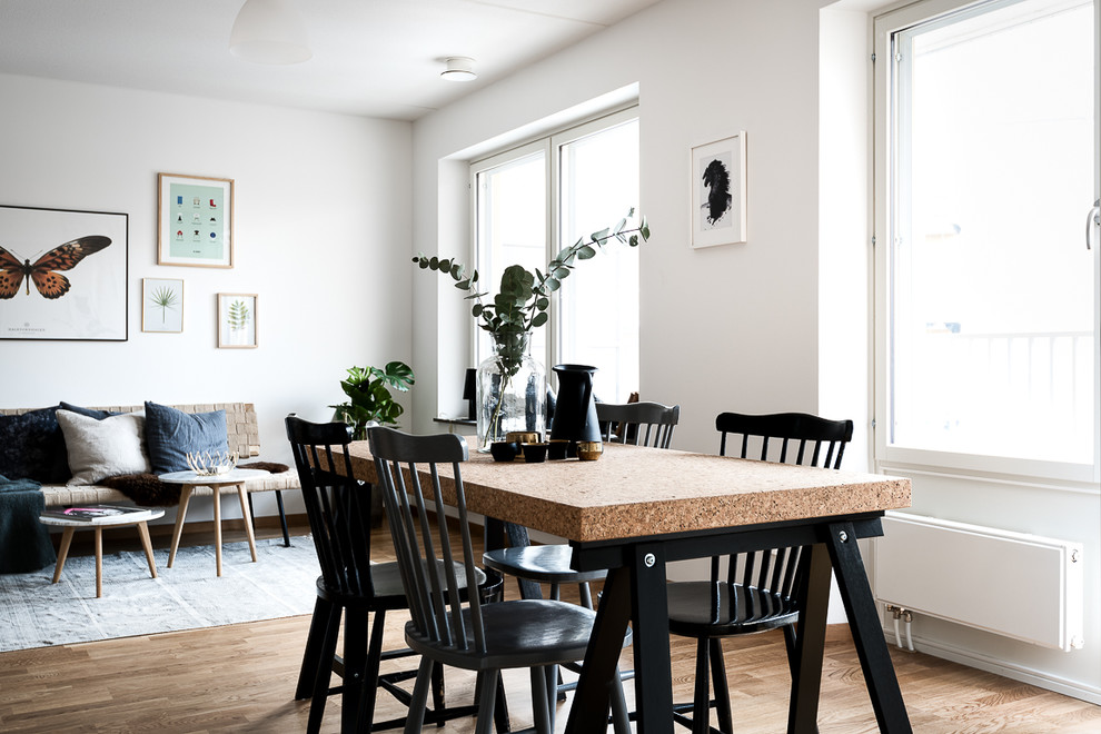 Bild på en mellanstor minimalistisk matplats med öppen planlösning, med vita väggar och ljust trägolv