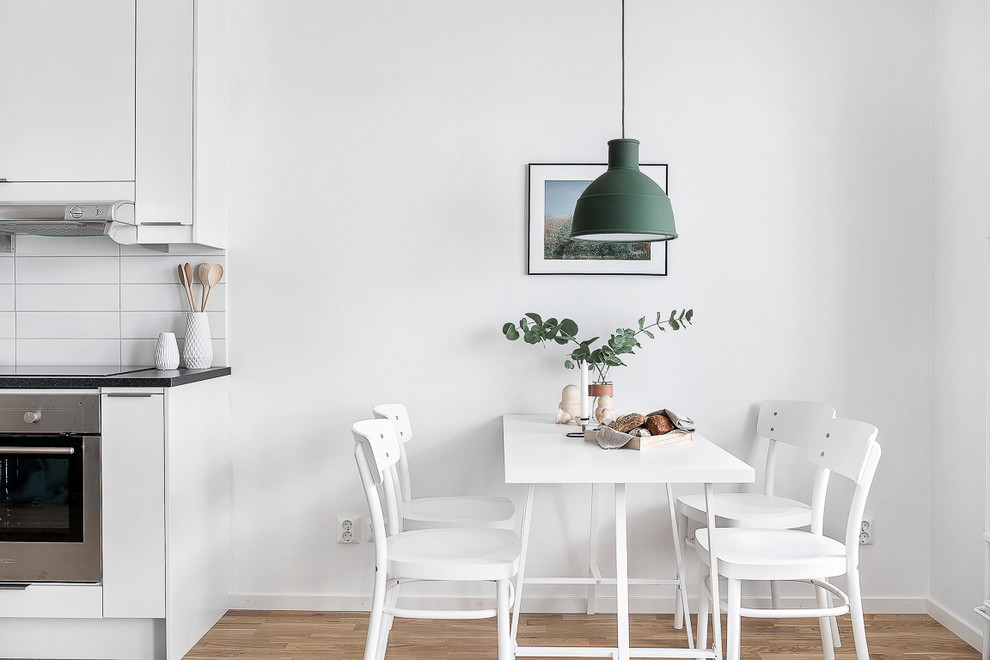 Foto de comedor de cocina escandinavo de tamaño medio sin chimenea con paredes blancas y suelo de madera clara