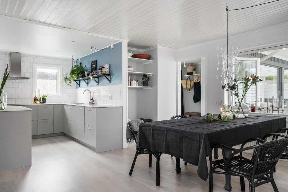 Idée de décoration pour une salle à manger ouverte sur le salon nordique de taille moyenne avec un mur bleu et parquet clair.