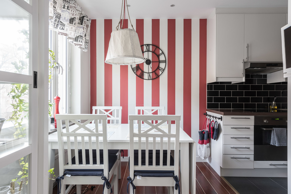 Inredning av ett minimalistiskt litet kök med matplats, med röda väggar, mörkt trägolv och brunt golv