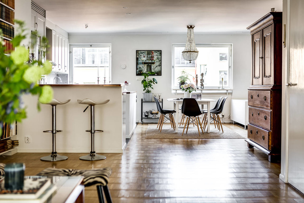 Dining room - mid-sized transitional medium tone wood floor dining room idea in Stockholm with white walls