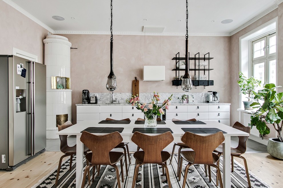 На фото: кухня-столовая среднего размера в скандинавском стиле с светлым паркетным полом, бежевым полом, розовыми стенами и угловым камином с