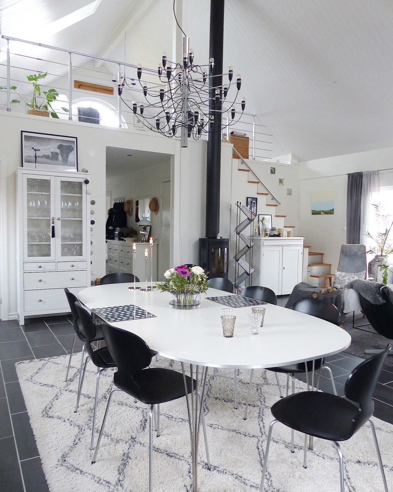 Immagine di una sala da pranzo aperta verso il soggiorno scandinava di medie dimensioni con pareti bianche, pavimento in gres porcellanato e pavimento nero