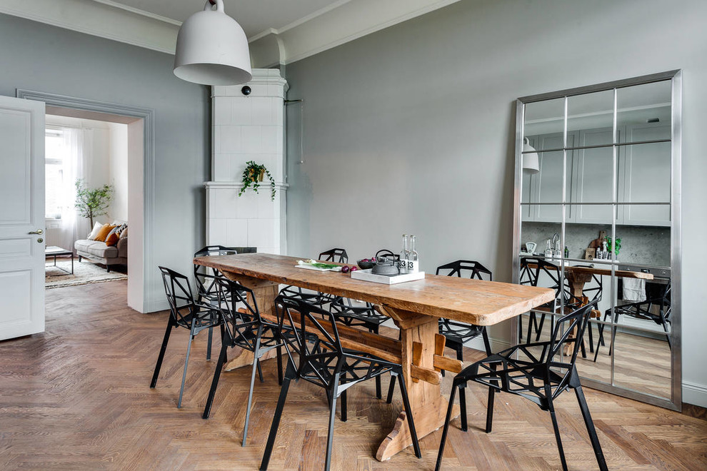 Источник вдохновения для домашнего уюта: большая отдельная столовая в скандинавском стиле с серыми стенами, паркетным полом среднего тона и печью-буржуйкой