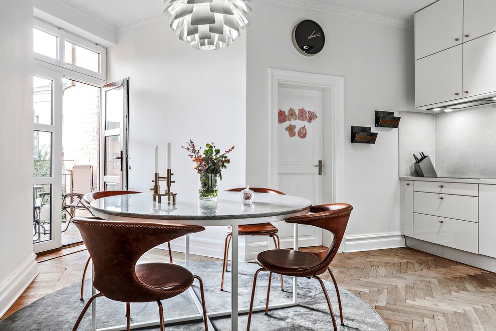 Cette image montre une salle à manger ouverte sur la cuisine nordique de taille moyenne avec parquet clair, un sol beige et un mur blanc.