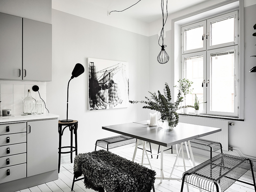 Ispirazione per una sala da pranzo aperta verso la cucina scandinava di medie dimensioni con pareti bianche, pavimento in legno verniciato e nessun camino