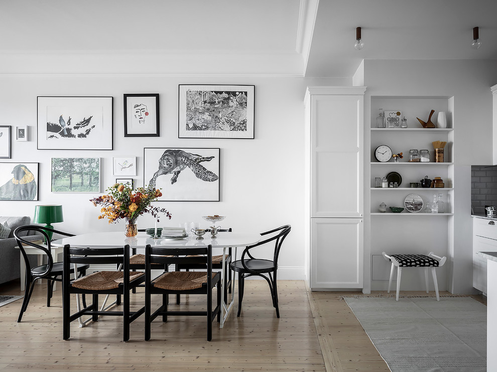 Cette image montre une salle à manger ouverte sur le salon nordique avec un mur blanc, parquet clair et un sol beige.
