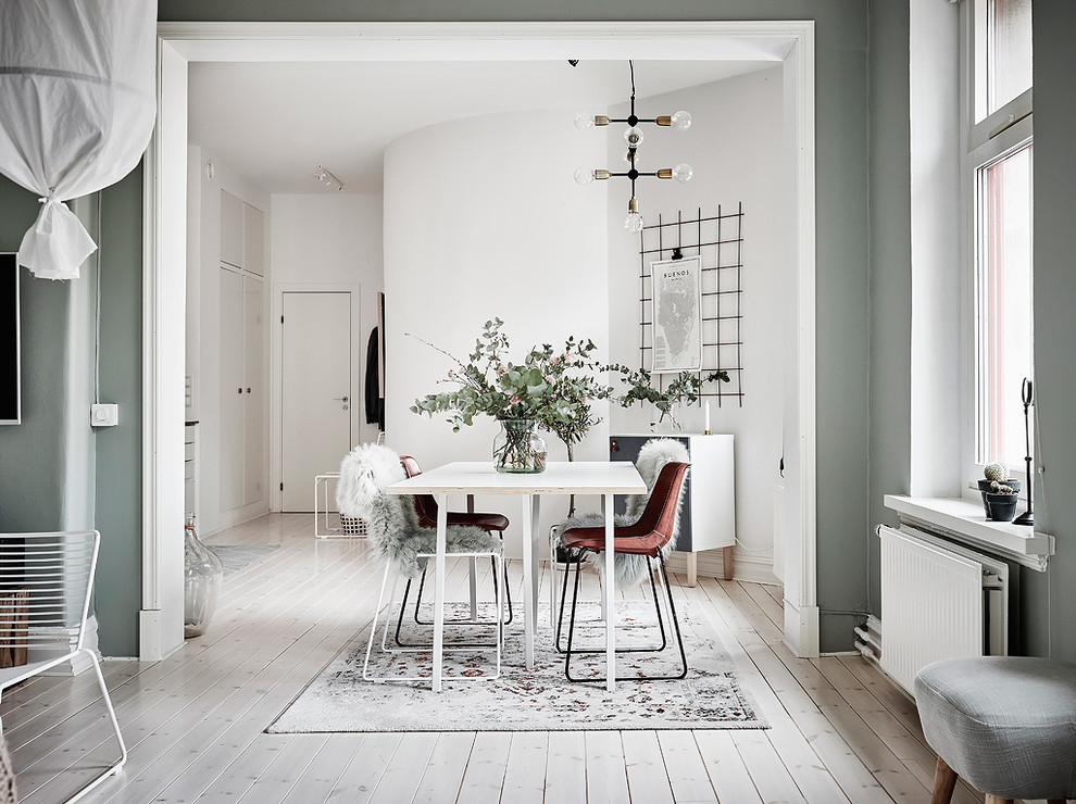 Immagine di una grande sala da pranzo aperta verso il soggiorno scandinava con parquet chiaro, pavimento bianco e pareti verdi