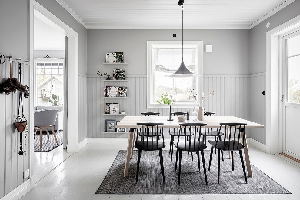 Cette image montre une salle à manger nordique fermée avec un mur gris, parquet peint, aucune cheminée et un sol blanc.