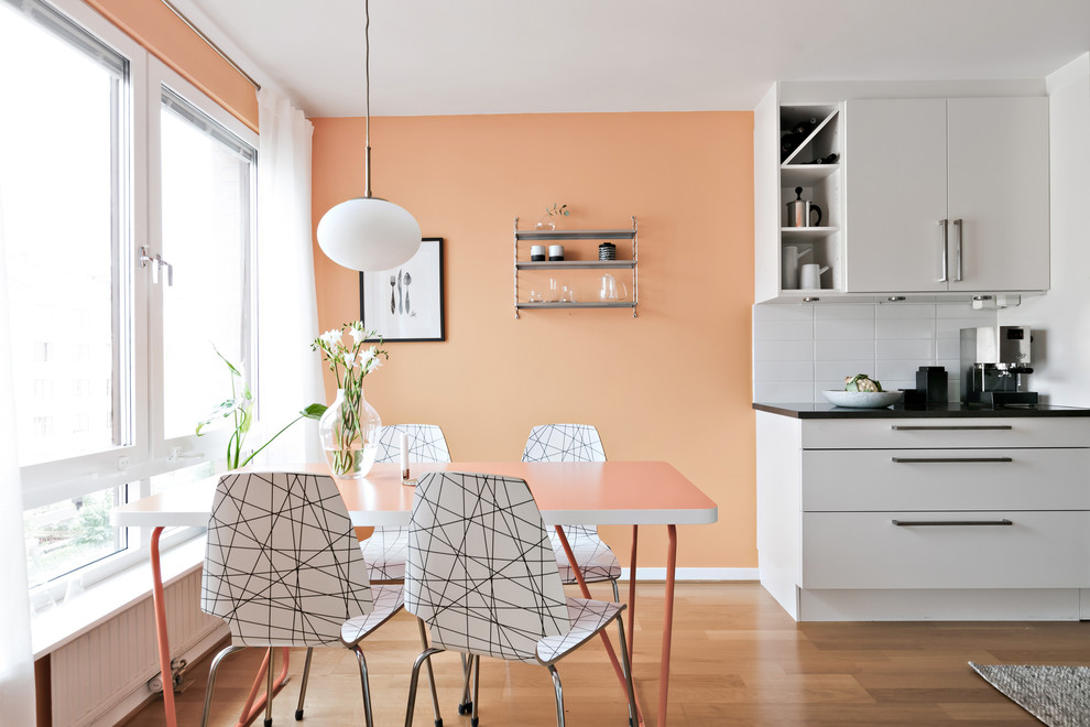 Foto di una sala da pranzo aperta verso la cucina nordica con pareti arancioni, pavimento in legno massello medio e pavimento marrone