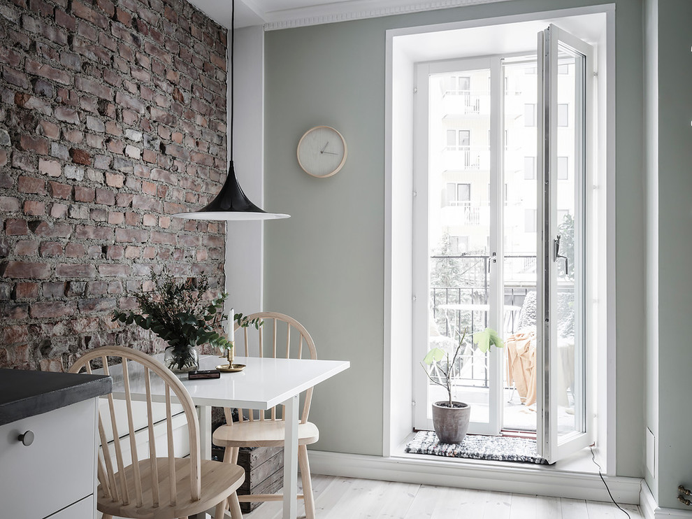 Immagine di una piccola sala da pranzo aperta verso la cucina scandinava con pareti multicolore, parquet chiaro e pavimento beige