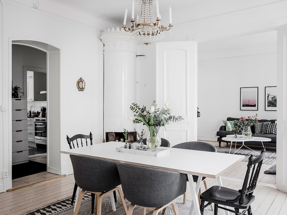 Idee per una sala da pranzo scandinava chiusa con pareti bianche, parquet chiaro, camino ad angolo e pavimento beige