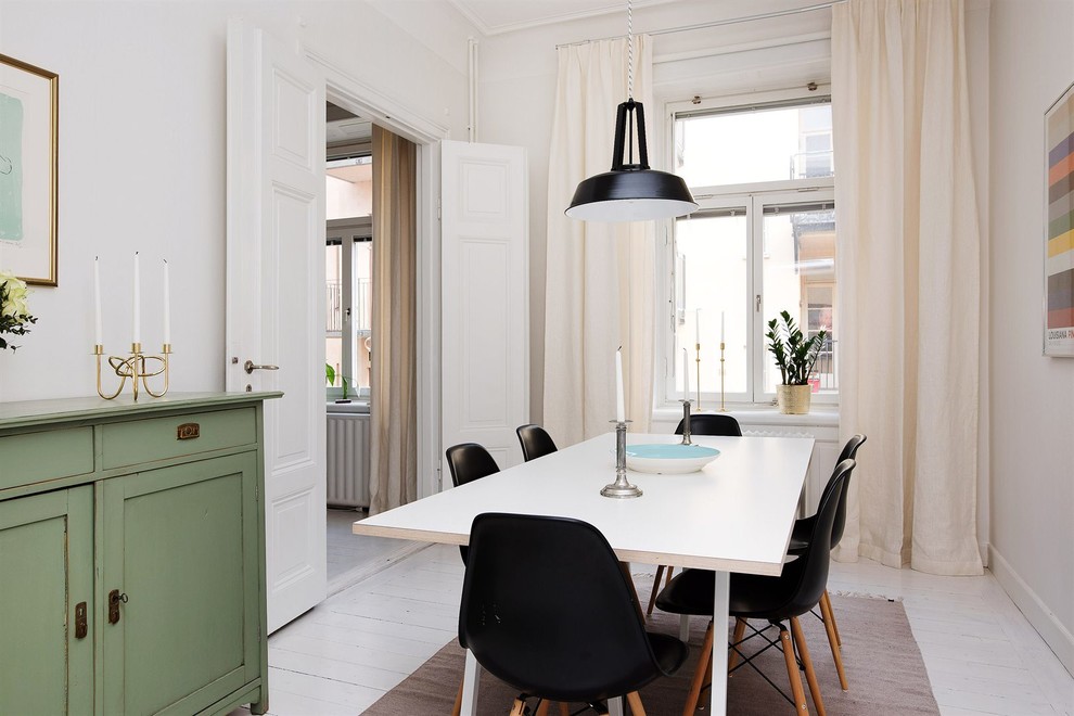 This is an example of a medium sized scandi enclosed dining room in Stockholm with white walls, painted wood flooring and no fireplace.