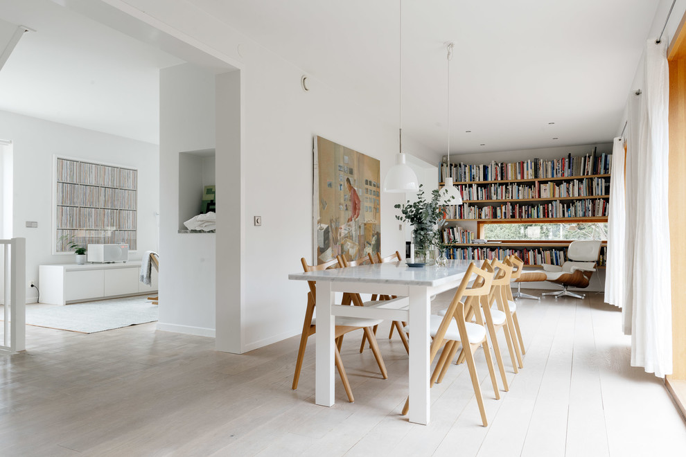 Foto di un'ampia sala da pranzo aperta verso la cucina scandinava con pareti bianche e pavimento in legno verniciato
