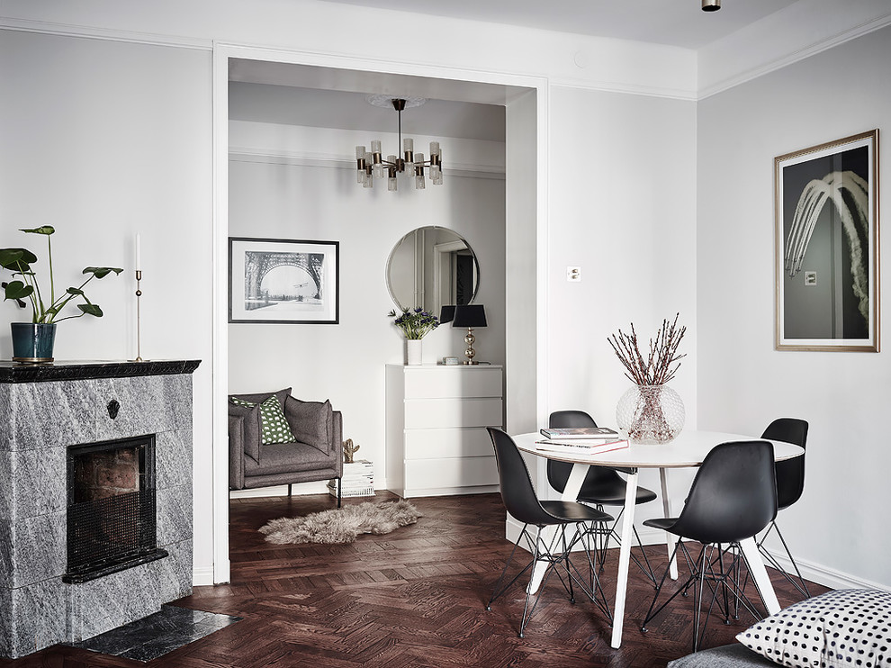 Inspiration for a scandinavian enclosed dining room in Gothenburg with grey walls, dark hardwood flooring, a standard fireplace, a stone fireplace surround and brown floors.