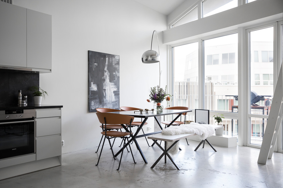 Immagine di una sala da pranzo nordica con pareti bianche, pavimento in cemento e pavimento grigio