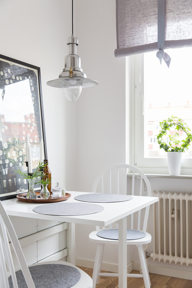 Inredning av en minimalistisk mellanstor separat matplats, med vita väggar och ljust trägolv
