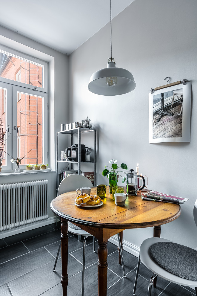 Immagine di una piccola sala da pranzo aperta verso la cucina nordica con pareti grigie e pavimento nero