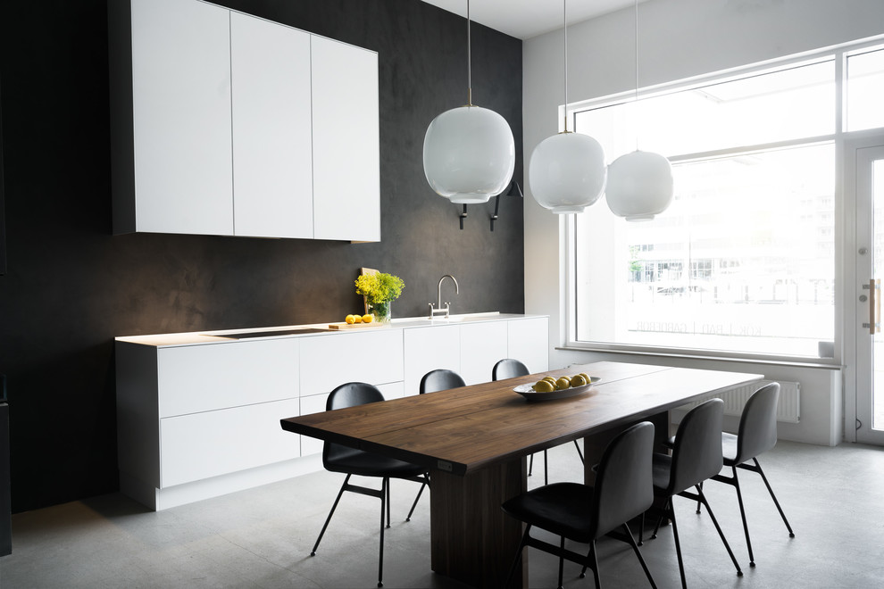 Minimalistisk inredning av ett mellanstort kök med matplats, med grå väggar, betonggolv och grått golv
