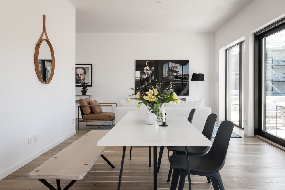 Foto på en mellanstor minimalistisk matplats med öppen planlösning, med vita väggar, beiget golv och ljust trägolv