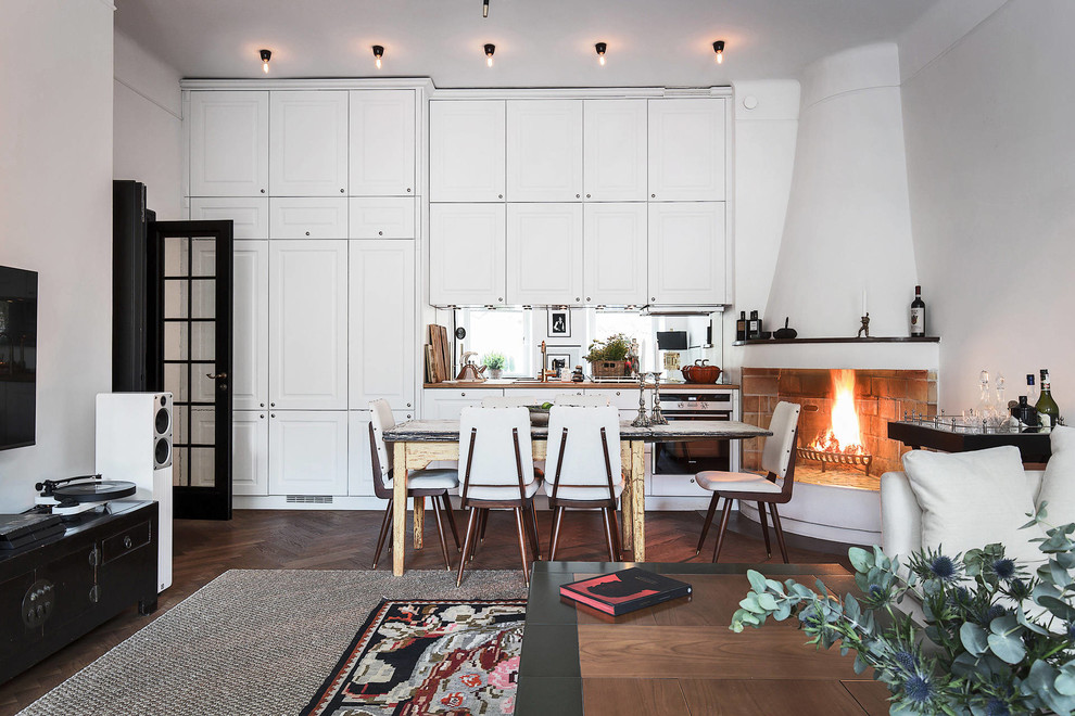Ejemplo de comedor de cocina nórdico grande con paredes blancas, suelo de madera oscura, chimenea de esquina y marco de chimenea de yeso